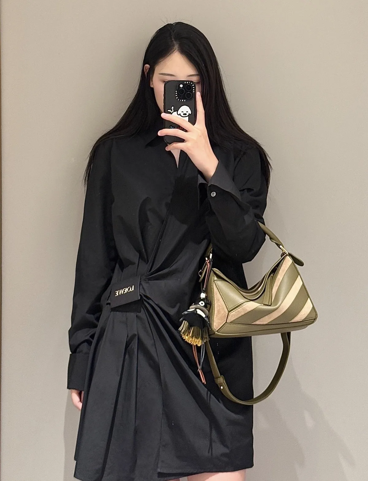 Olive and pale beige shoulder bag beside a black collared, belted outfit